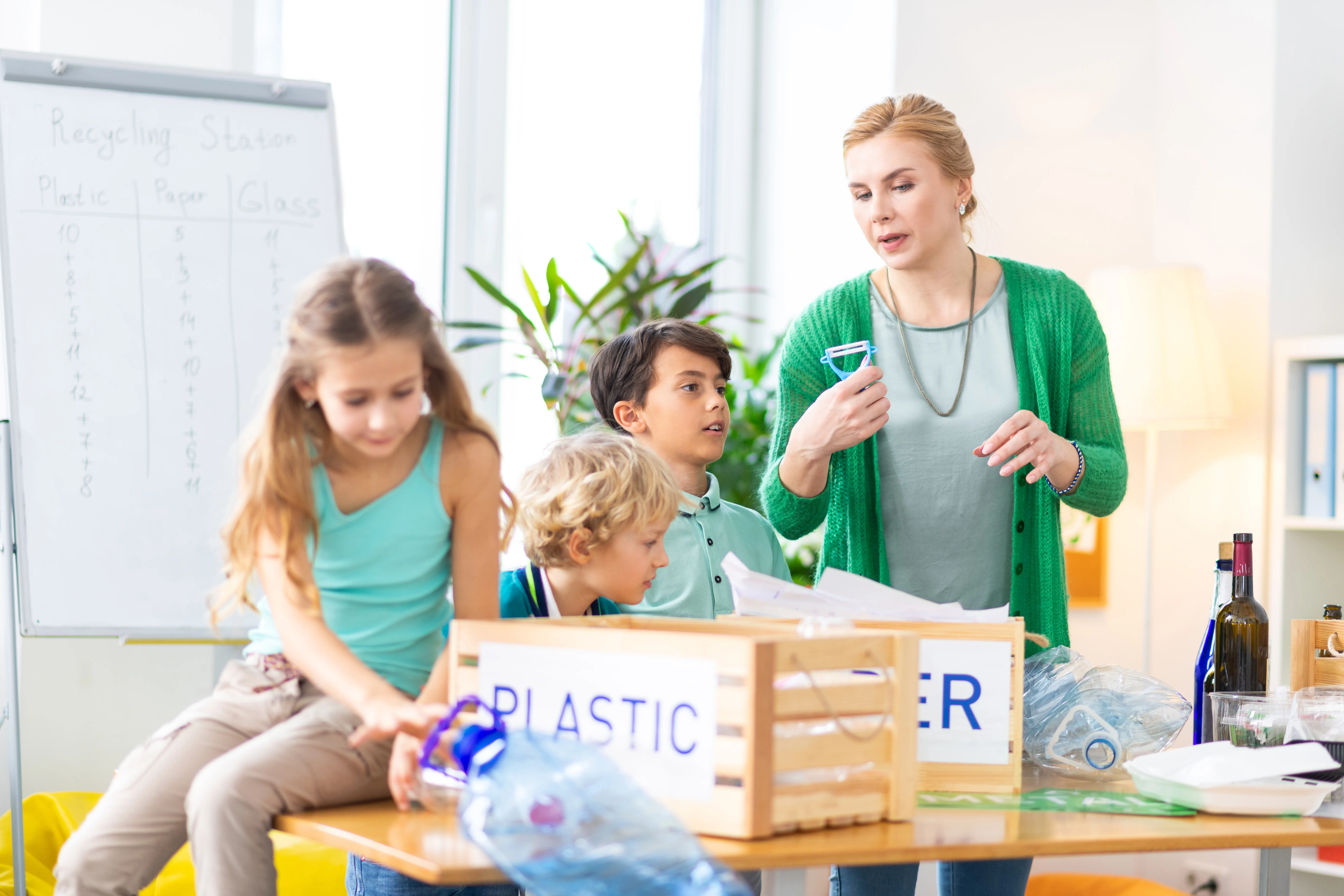 Die Bedeutung des Sortierens. Eine hilfsbereite Grundschullehrerin erklärt ihren Schülern, warum Mülltrennung wichtig ist.